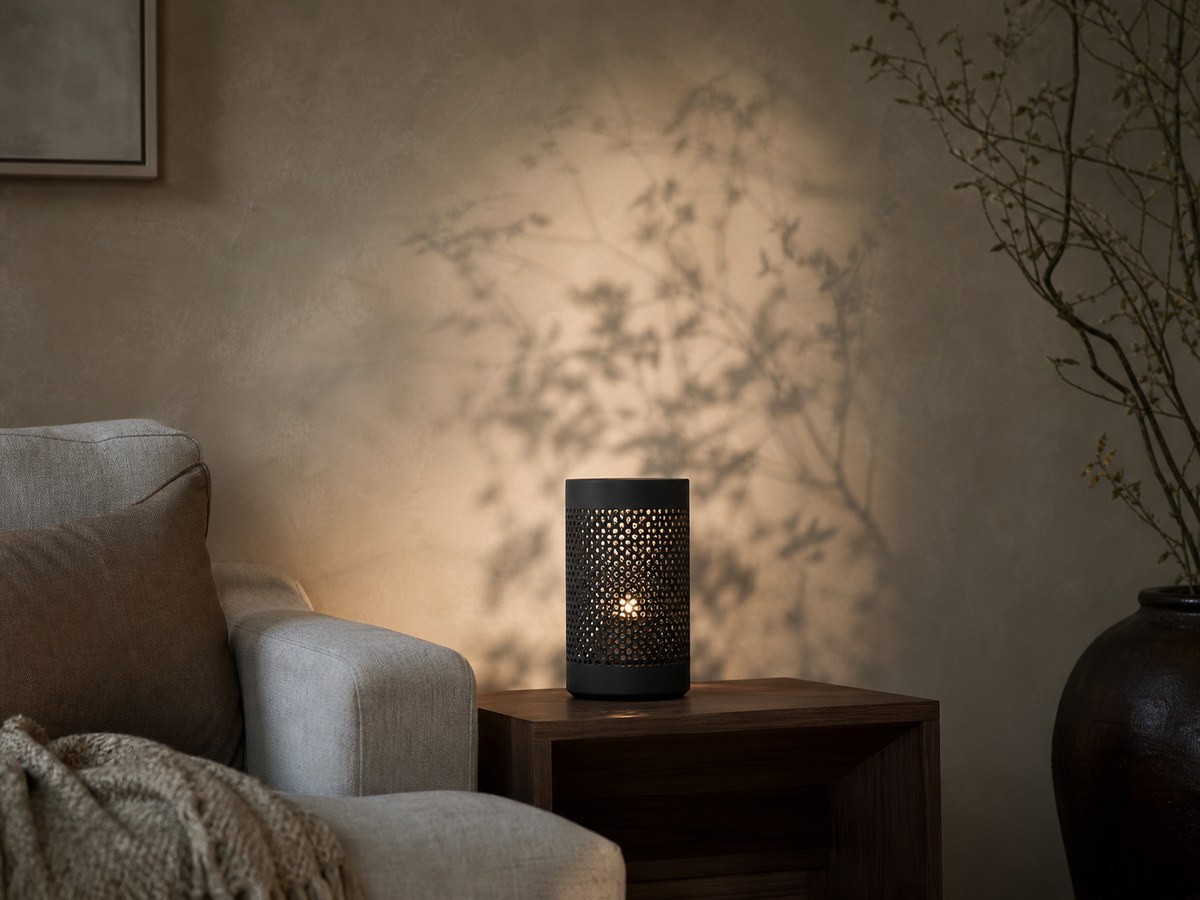 Black tree-pattern lamp casting branch shadows across a warm plaster wall