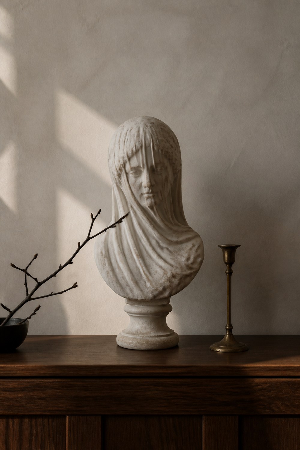 Antiqued white veiled bust on a walnut console with a single black branch
